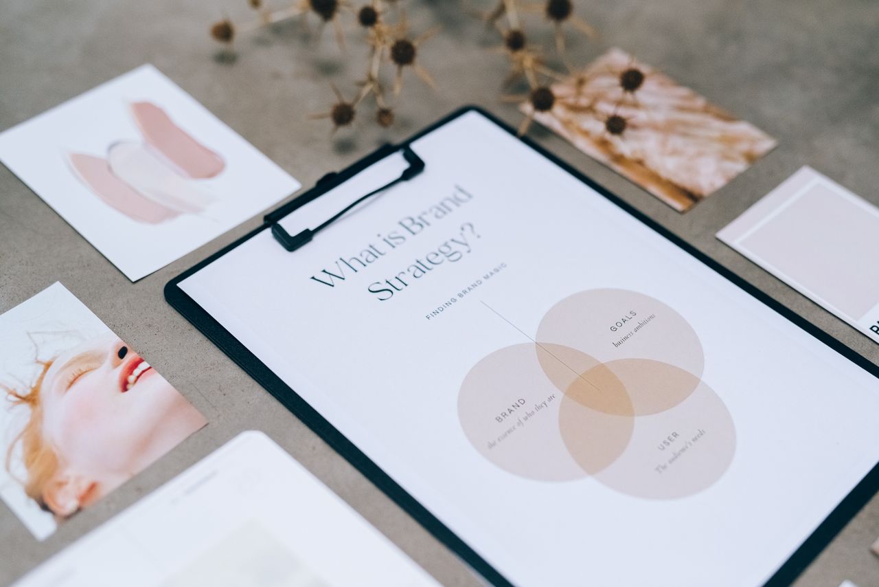 A close-up view of a brand strategy document on a desk surrounded by design artworks.